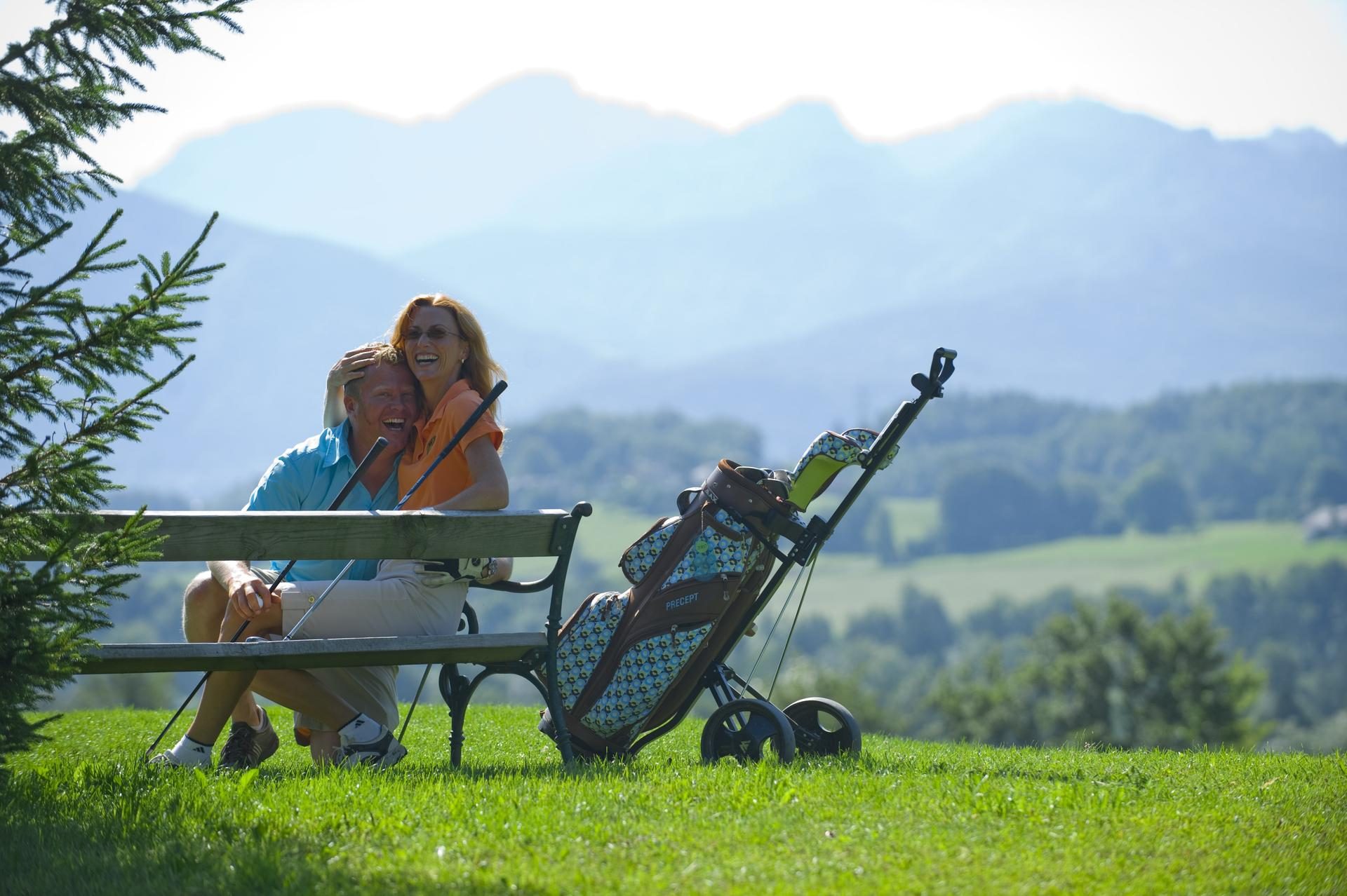 Paar auf einer Bank mit Blick auf Berge und Wald am Golfclub Salzkammergut