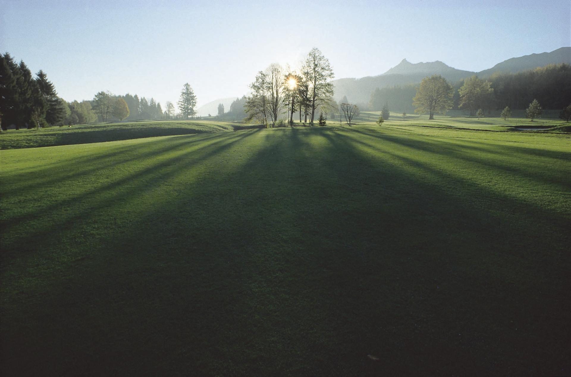 Weitläufige Rasenfläche des Golfclub Salzkammergut mit bewaldeten Bergen