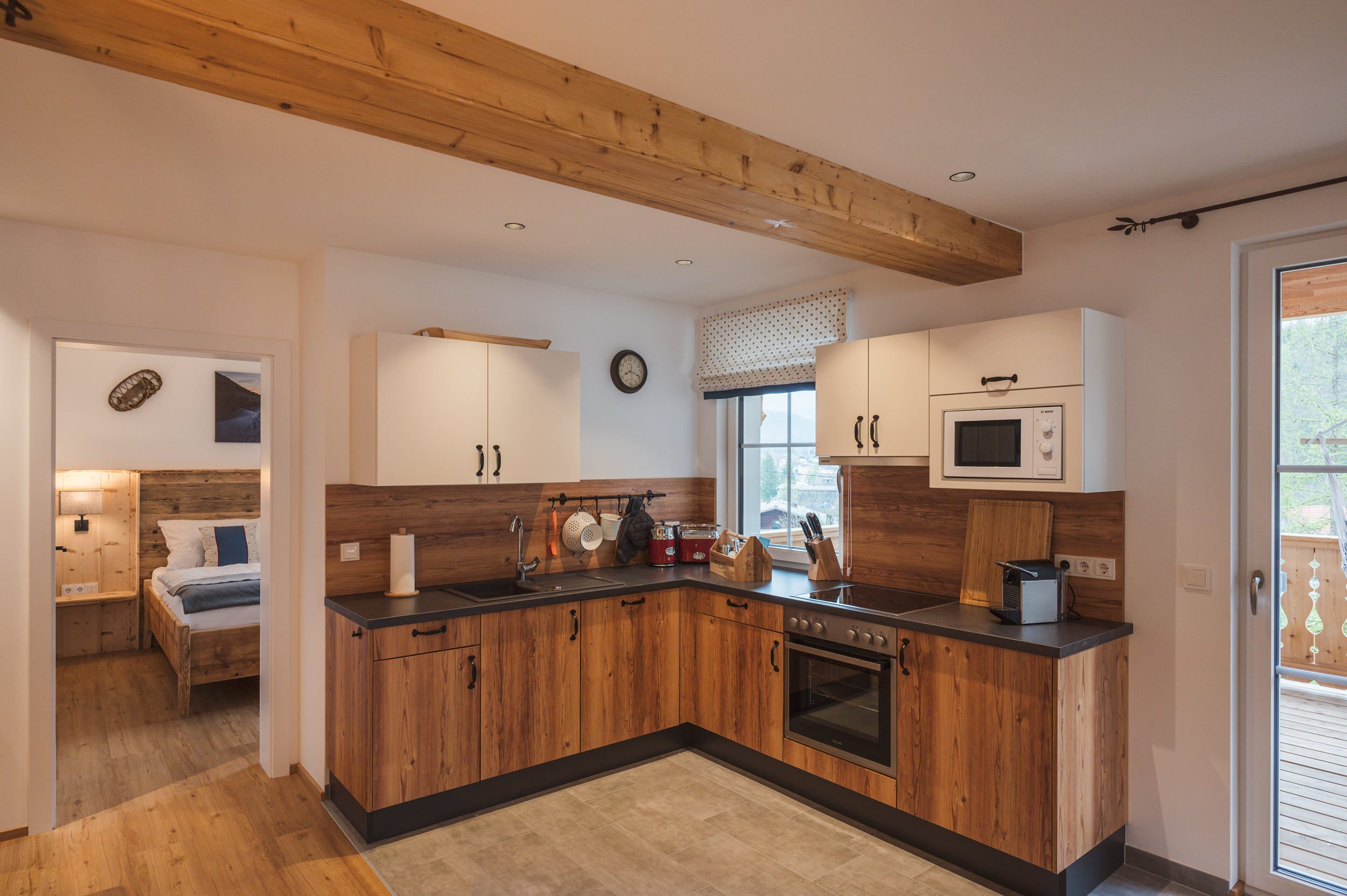 L-förmige Küche mit Holzfronten und Blick ins Schlafzimmer