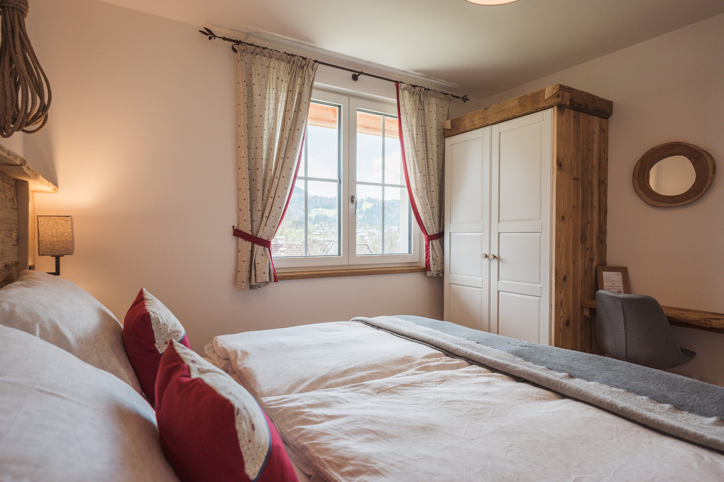 Schlafzimmer 1 mit weißem Schrank und Bergblick durchs Fenster