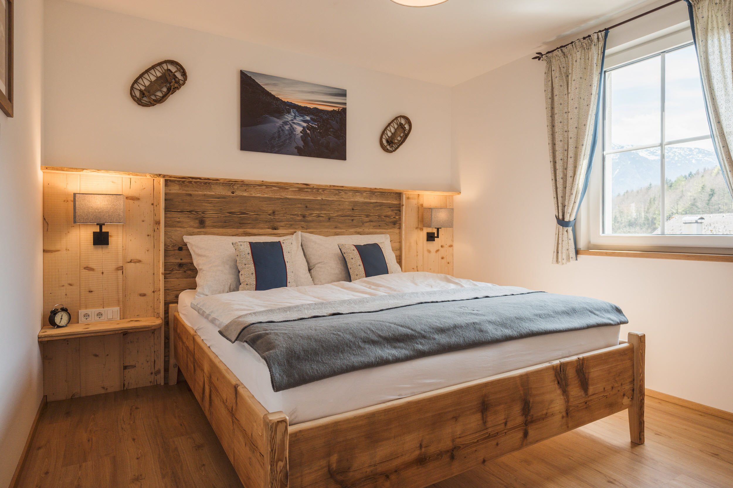 Schlafzimmer 2 mit Altholzbett, Bergpanorama-Bild und blauen Akzentkissen