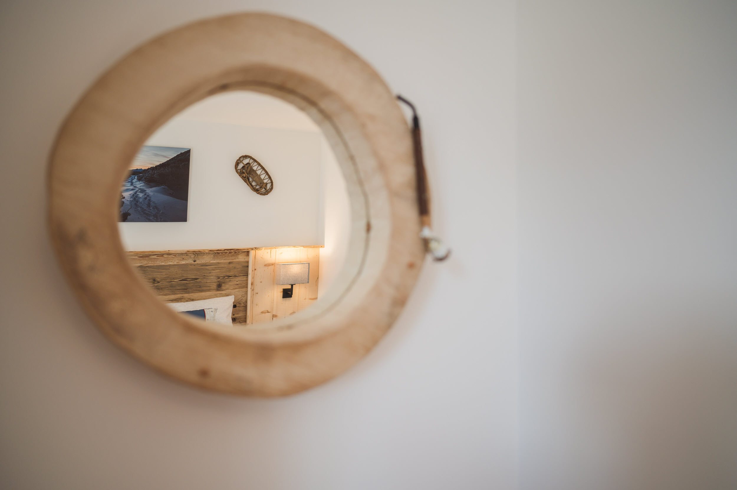 Detail: runder Spiegel aus Holz mit Blick auf Bett und Bergsteiger-Foto