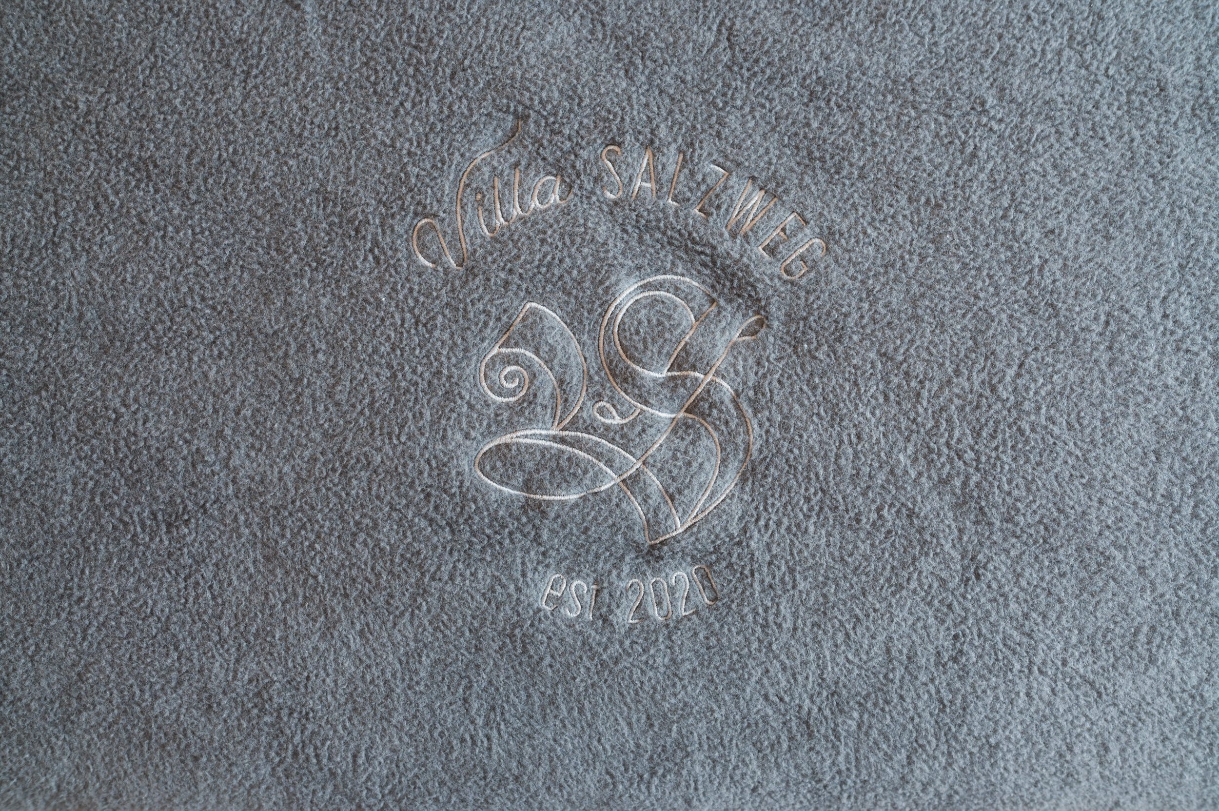 Villa-Salzweg-Logo auf der grauen Kuscheldecke