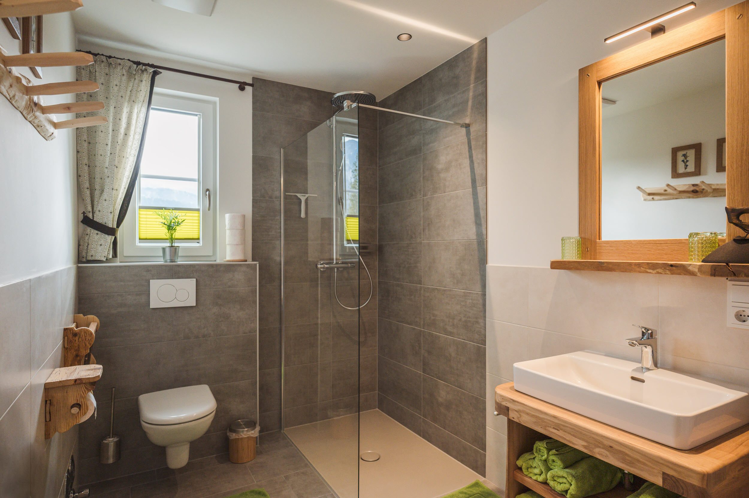 Badezimmer mit Walk-In-Regendusche und grünen Handtüchern