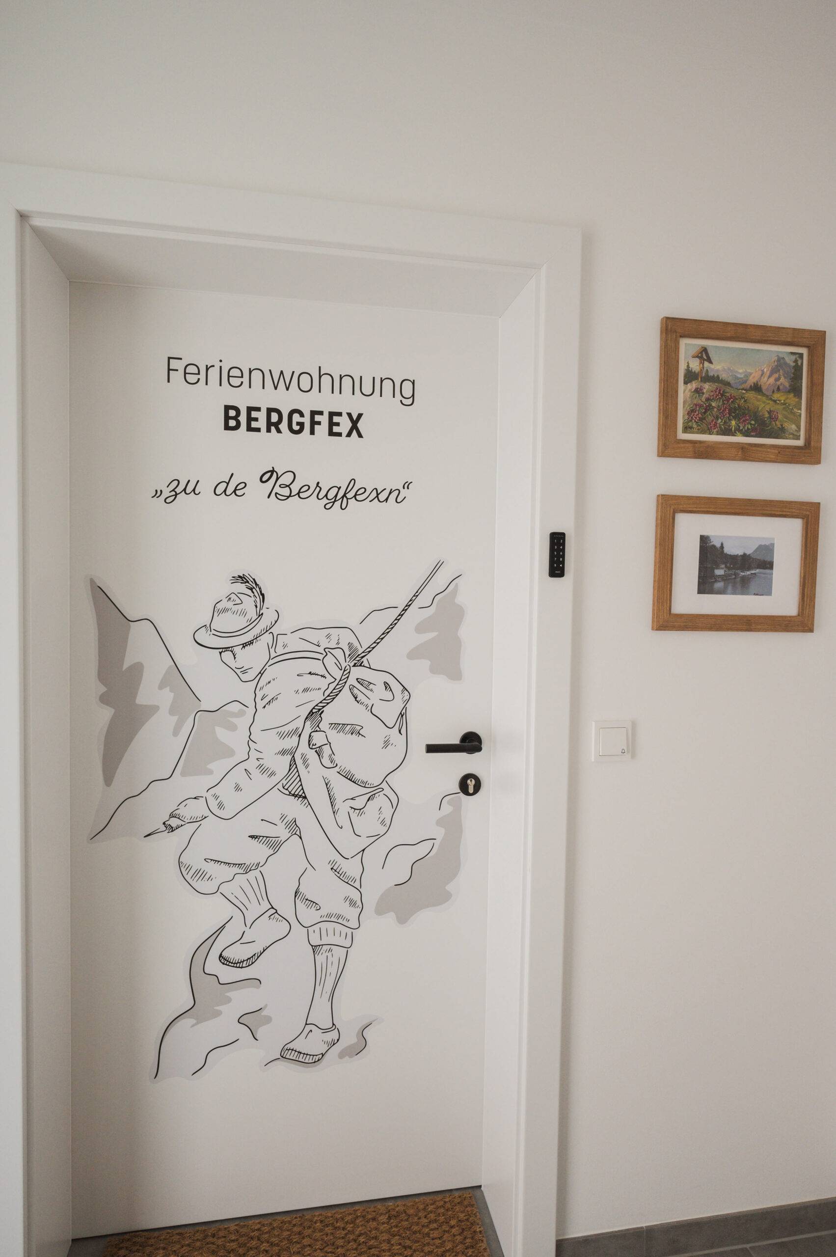 Eingangstür der Bergfex-Wohnung mit gezeichnetem Bergsteiger