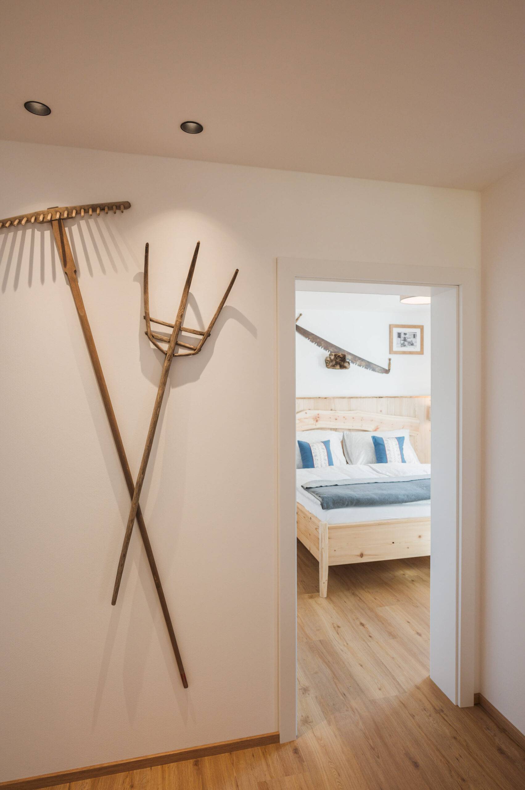 Handwerker-Wohnung: Flur mit Holzrechen und Heugabel, Blick ins Schlafzimmer