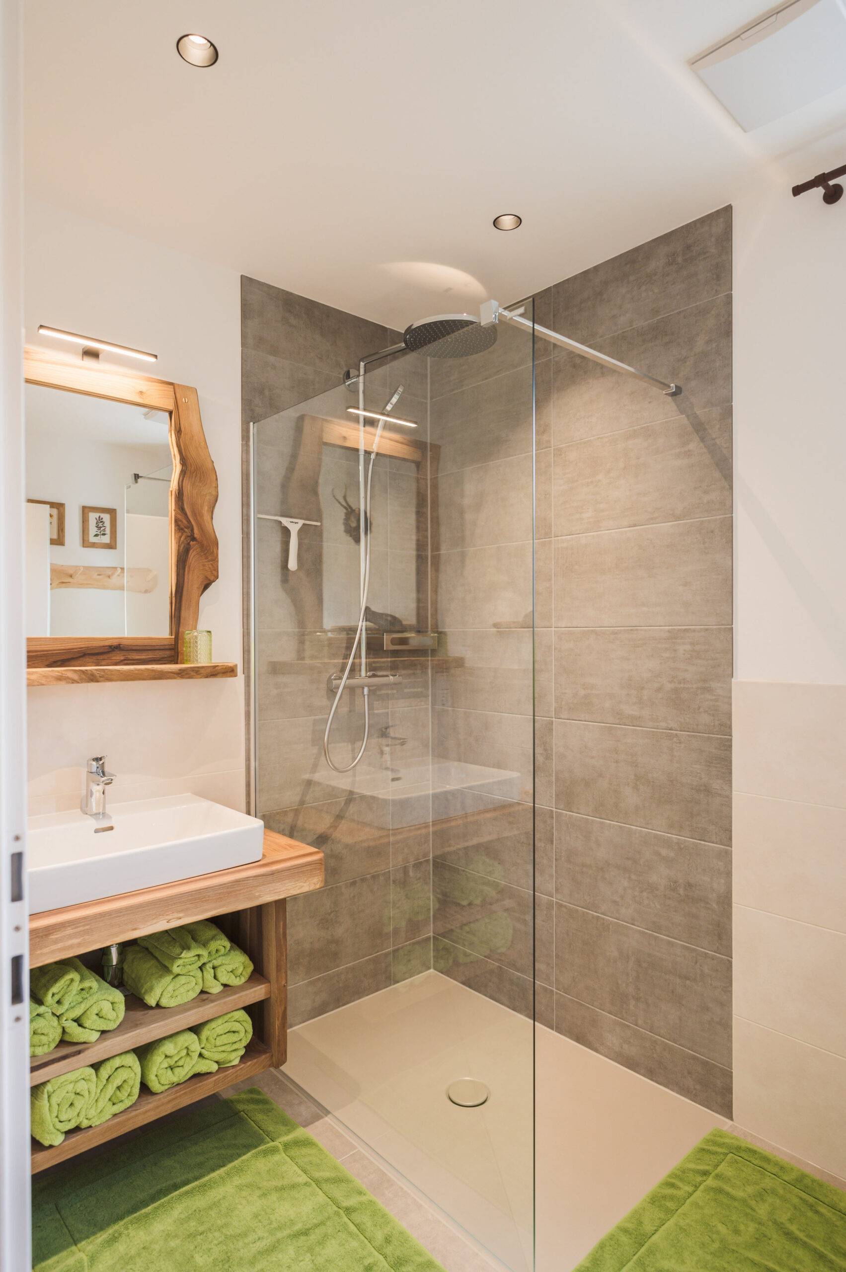 Wilderer-Wohnung: Badezimmer mit Walk-In-Regendusche und grünen Handtüchern