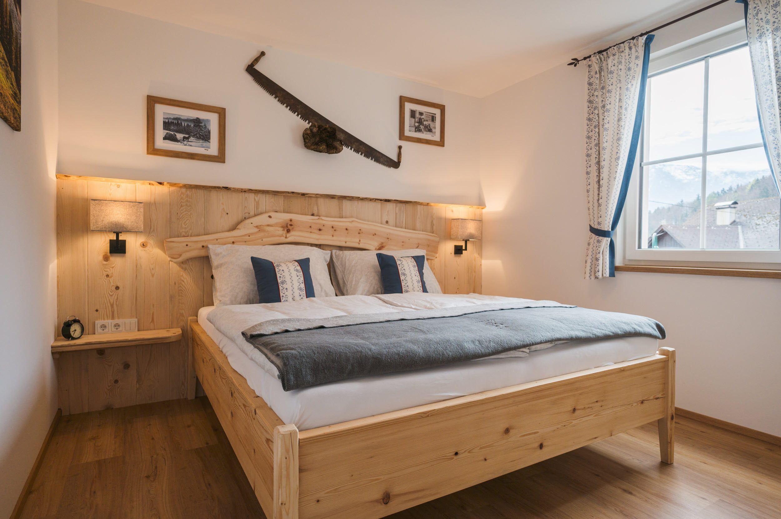 Schlafzimmer 1 mit Zirbenbett und Holzsäge an der Wand