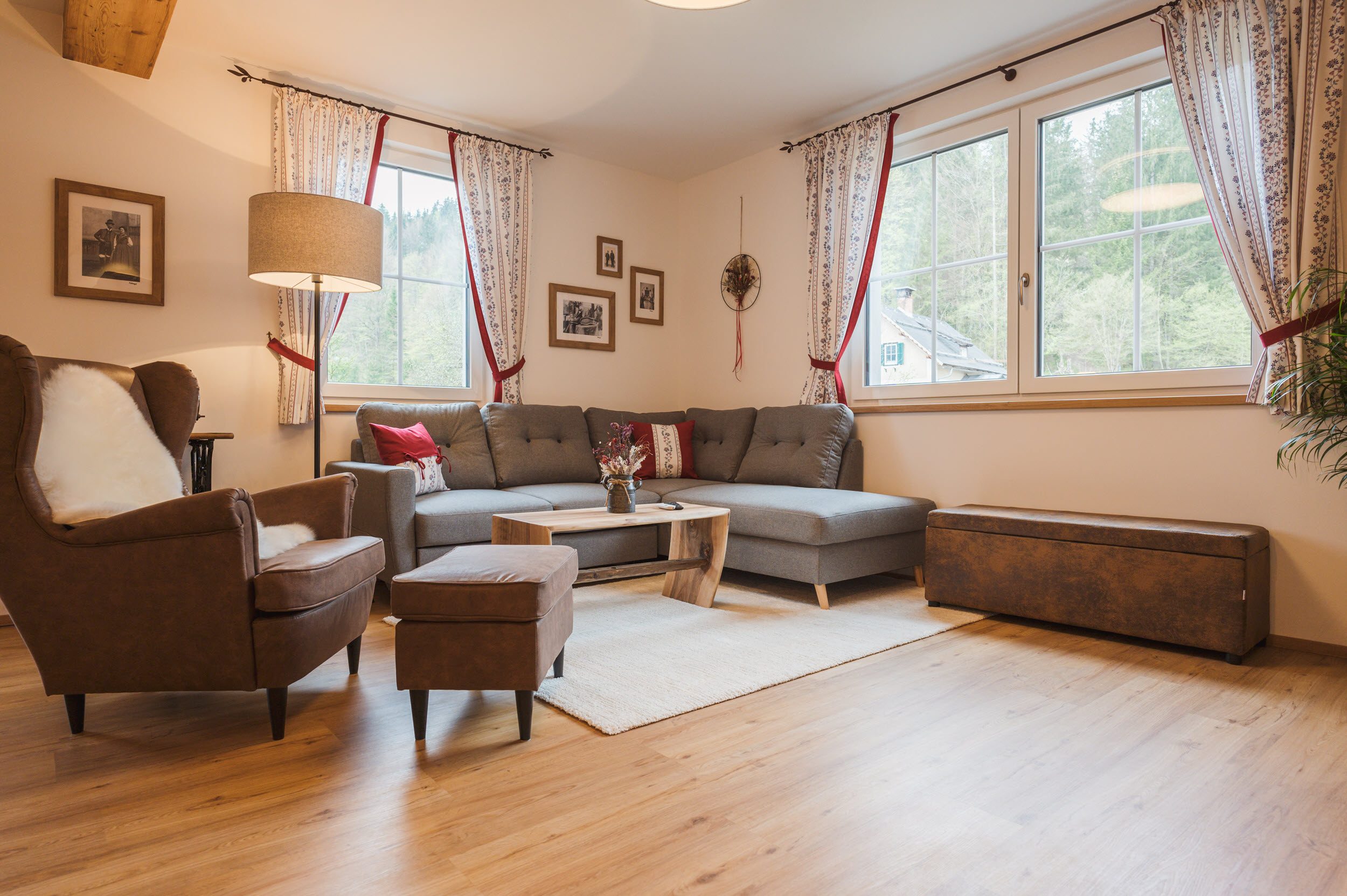 Wohnzimmer mit grauer Eckcouch, Ledersessel und braunem Hocker