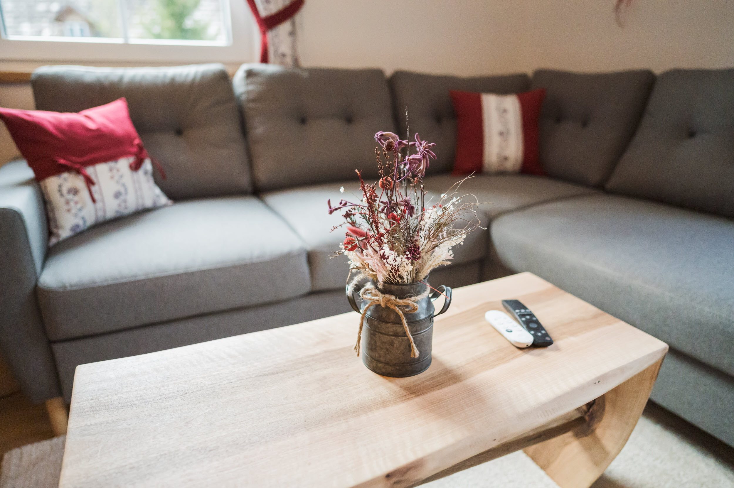 Couch-Detail: Trockenblumen in Zinkkanne auf Holz-Couchtisch