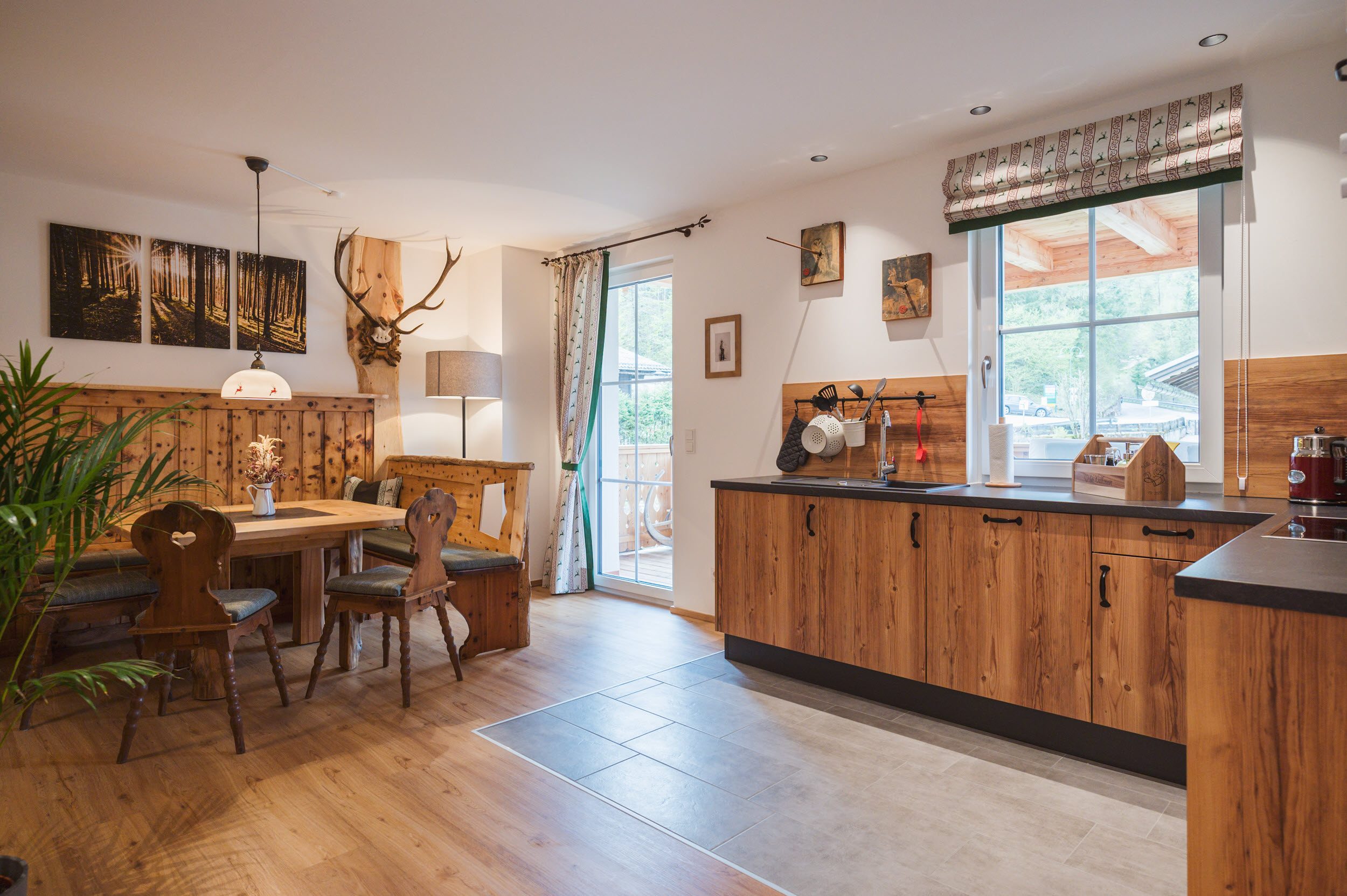 Wohn-Essbereich mit Hirschgeweih, Holz-Esstisch und Blick zur Küche
