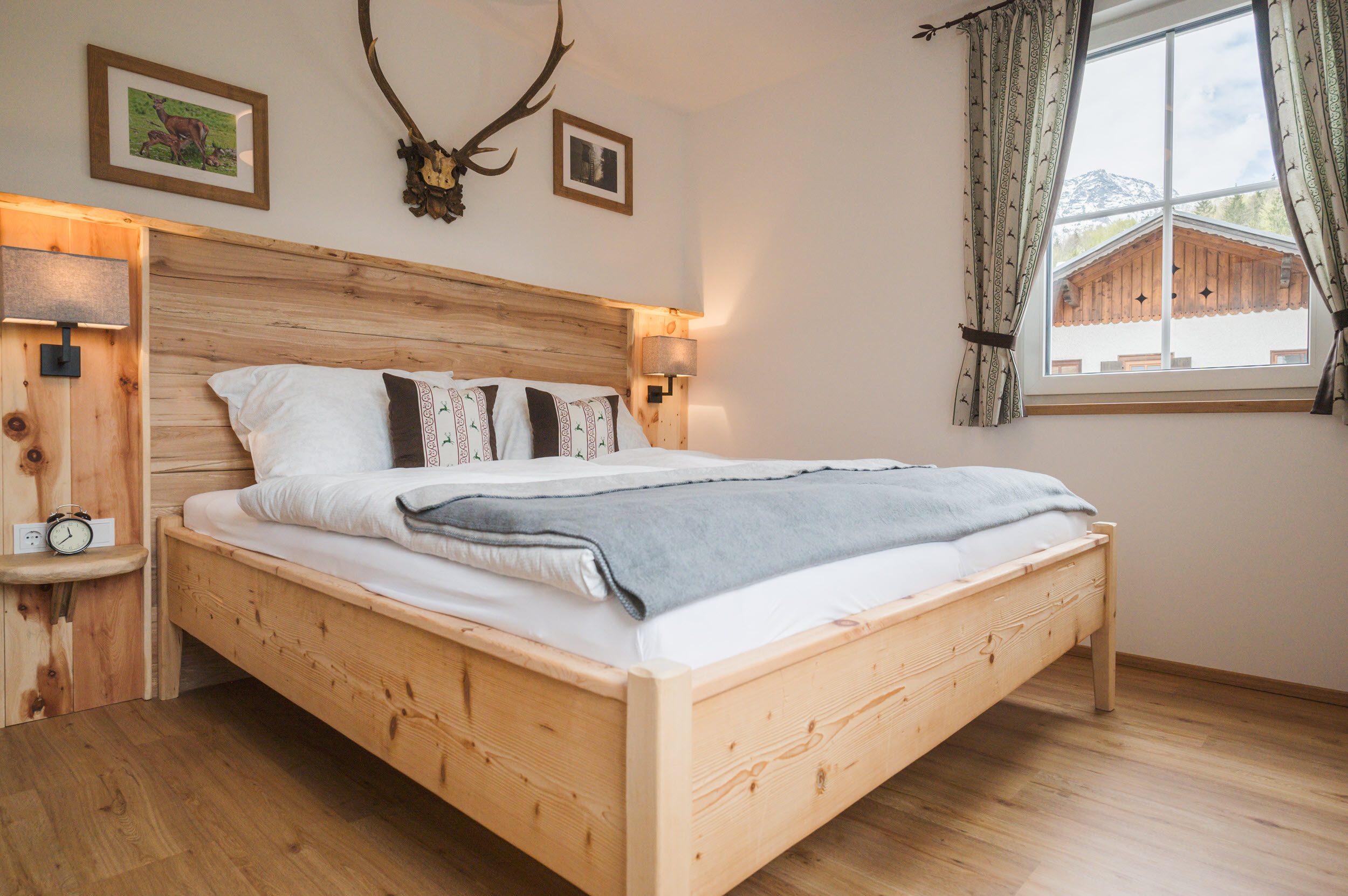 Schlafzimmer 1 mit Doppelbett aus Zirbenholz und Geweih über dem Bett